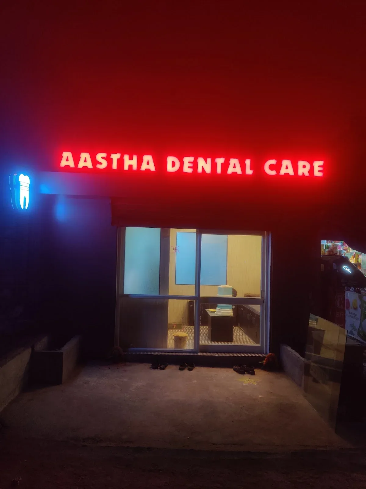 Illuminated Aastha Dental Care sign above the entrance